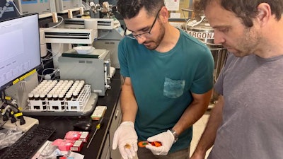 UC Davis Ph.D. candidate Mark Salazar, left, holds a disposable vape pod in the lab with Brett Poulin, a UC Davis assistant professor of environmental toxicology.
