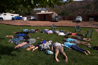 Participants lay face down on the grass during an integration circle at an ayahuasca retreat in Hildale, Utah, Oct. 15, 2022.
