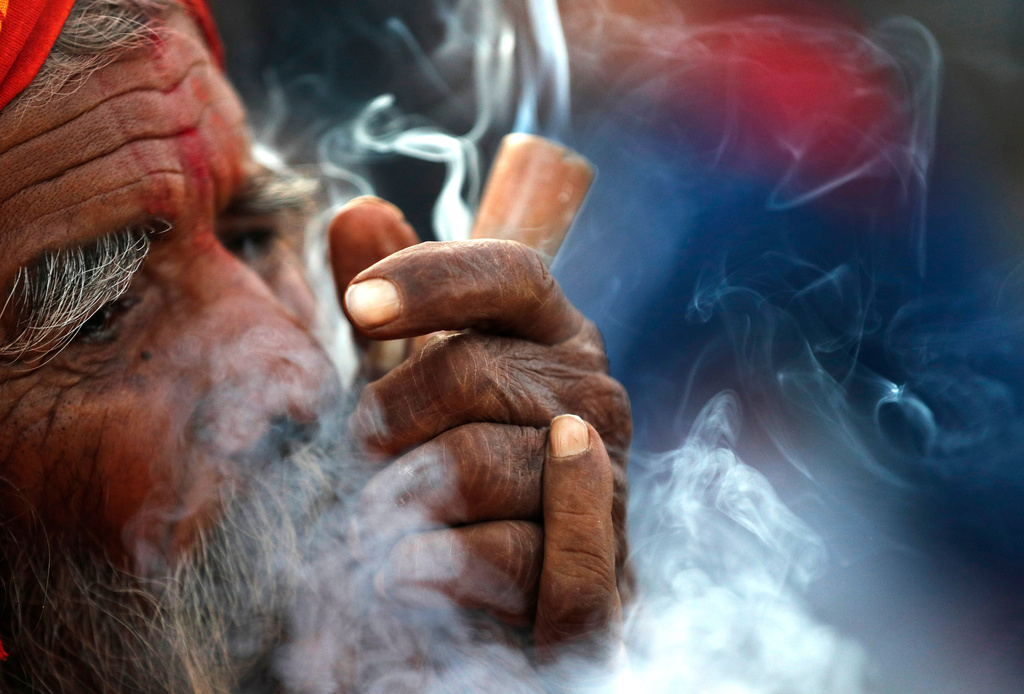 In this March 11, 2021, file photo, a Hindu holy man smokes marijuana in the courtyard of Pashupatinath temple during Shivratri festival in Kathmandu, Nepal.