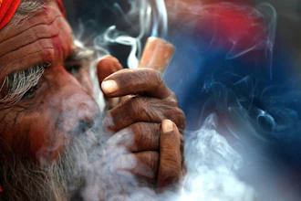 In this March 11, 2021, file photo, a Hindu holy man smokes marijuana in the courtyard of Pashupatinath temple during Shivratri festival in Kathmandu, Nepal.