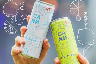Two hands holding CANN natural tonic cans in blue grapefruit rosemary and yellow lemon lavender flavors at an outdoor event