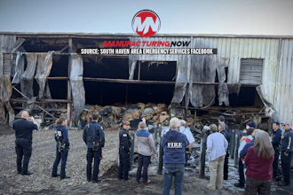 Emergency responders and firefighters assess damage at industrial warehouse with collapsed roof and debris