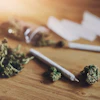 Cannabis buds and rolling papers arranged on wooden surface with smoking accessories