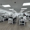 Modern laboratory workspace with multiple workstations, white cabinetry, LED lighting, and staff conducting research or analysis