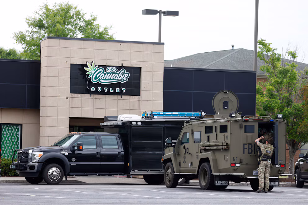 Law enforcement vehicles parked outside Cornubia Outlet storefront with armed personnel present