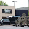 Law enforcement vehicles parked outside Cornubia Outlet storefront with armed personnel present