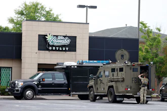 Law enforcement vehicles parked outside Cornubia Outlet storefront with armed personnel present