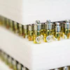 Tiered display of yellow-tinted fragrance bottles with metallic caps and white emblems arranged on white shelving