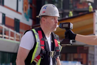 Construction worker wearing safety helmet and reflective vest holding surveying equipment on active job site
