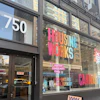 Housing Works storefront at 750 with pink signage, LGBTQIA+ community care messaging, and cannabis dispensary window display on urban street