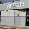 Curaleaf dispensary storefront with green logo, blue pillar, and dark entrance doors at address 5400