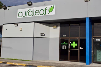 Curaleaf dispensary storefront with green logo, blue pillar, and dark entrance doors at address 5400