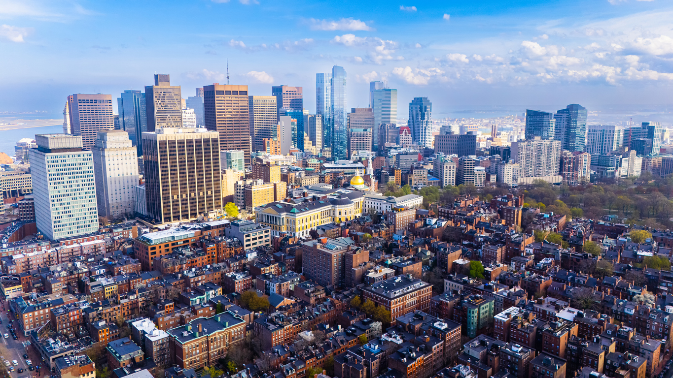 Aerial view of downtown city skyline with tall skyscrapers, residential neighborhoods, and blue sky with clouds