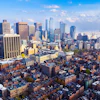 Aerial view of downtown city skyline with tall skyscrapers, residential neighborhoods, and blue sky with clouds