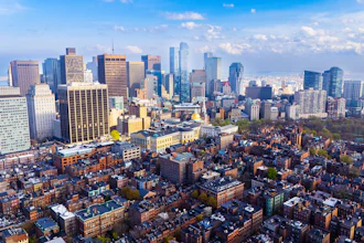 Aerial view of downtown city skyline with tall skyscrapers, residential neighborhoods, and blue sky with clouds