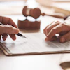 Two professionals reviewing and signing a legal document at a desk with a rubber stamp nearby