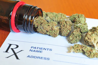 Medical cannabis buds spilling from prescription bottle onto Rx prescription pad against orange background