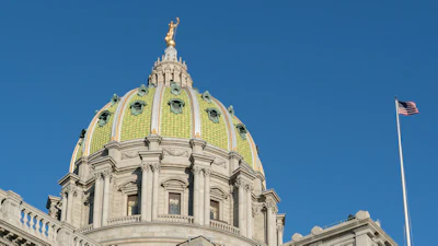 Pennsylvania State Capitol building with distinctive golden dome and classical architecture against clear blue sky