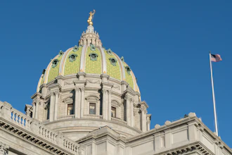 Pennsylvania State Capitol building with distinctive golden dome and classical architecture against clear blue sky