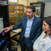 Man and woman examine data on computer monitor in laboratory with scientific equipment
