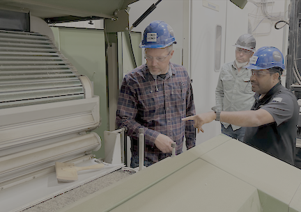 Industrial workers in hard hats discussing equipment at a manufacturing facility