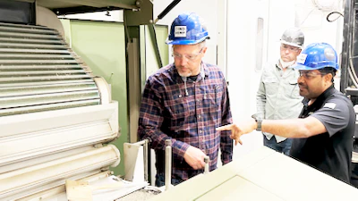 Industrial workers in hard hats discussing equipment at a manufacturing facility