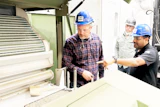 Industrial workers in hard hats discussing equipment at a manufacturing facility