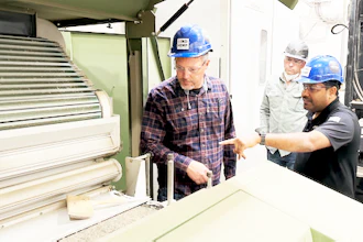 Industrial workers in hard hats discussing equipment at a manufacturing facility